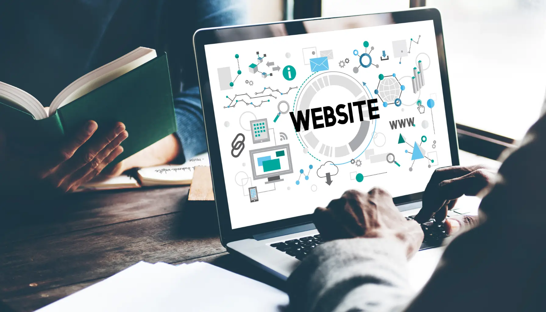 A person typing on a laptop displaying the word "WEBSITE," surrounded by digital icons, while holding a green book — representing the importance of website accessibility for business.
